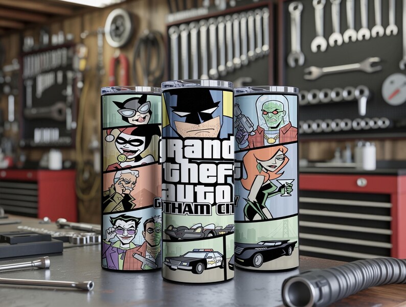 May include: Three cylindrical tumblers featuring a comic book style graphic wrap. The design displays various characters including Batman, Harley Quinn, and the Joker, alongside the text Grand Theft Auto Gotham City and illustrations of vehicles.