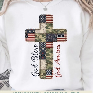 Puede incluir: Sudadera blanca con un diseño de cruz que incorpora patrones de la bandera estadounidense y camuflaje. La cruz tiene las palabras "God Bless" y "God America" en escritura cursiva. La imagen incluye el texto "HIGH QUALITY . 300DPI PNG . FILE."