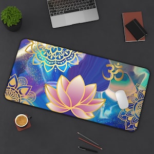 May include: A rectangular desk mat with a blue, purple, and gold abstract design. The mat features a pink lotus flower, gold mandala patterns, and the Om symbol. A white computer mouse rests on the mat.