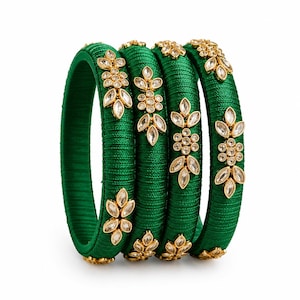 May include: A set of four emerald green bangles wrapped in thread, each featuring a repeating gold-tone metal floral motif set with clear, marquise-shaped and round crystals arranged in a vertical pattern along the outer surface of the bracelets.