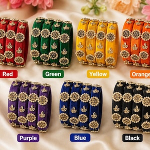May include: A collection of seven sets of bangles in red, green, yellow, orange, purple, blue, and black. Each set consists of four bangles featuring a velvet-like texture, adorned with circular gold-tone floral motifs and small leaf accents.