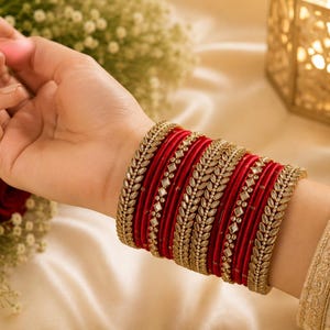 Peut inclure: Un ensemble de bracelets joncs rouges avec des accents métalliques dorés. La collection comprend des anneaux rouges unis alternés avec des anneaux dorés ornés de motifs en forme de feuilles et de petits carrés réfléchissants alignés.
