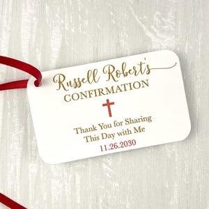 May include: White favor tag with a red ribbon. The tag says "Russell Robert's Confirmation" with a gold cross and the text "Thank You for Sharing This Day with Me 11.26.2030".