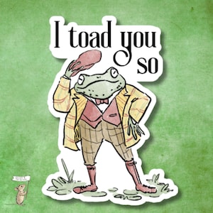 May include: A sticker featuring a dapper frog in a yellow plaid jacket, vest, and checkered pants, tipping a hat. The text "I toad you so" is above the frog. A small mouse holds a sign that says "Mouse & the Word".