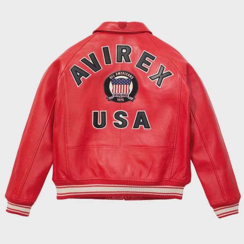 May include: A red leather jacket with the word "AVIREX" arched across the shoulders in black and white lettering. Below, the word "USA" is displayed. A circular patch with the American flag is centered between the words. The jacket has a collar and striped cuffs.