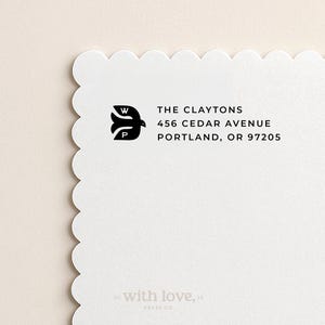 May include: White stationery with a scalloped edge. The black text reads "THE CLAYTONS, 456 CEDAR AVENUE, PORTLAND, OR 97205." A black bird logo with the letters "W" and "P" is above the address. The words "with love," are at the bottom.