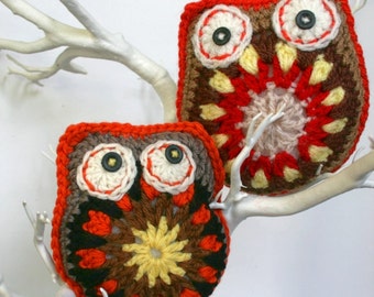May include: Two crocheted owl ornaments with red, brown, yellow, and white yarn. The owls have large, round eyes with black buttons for pupils.