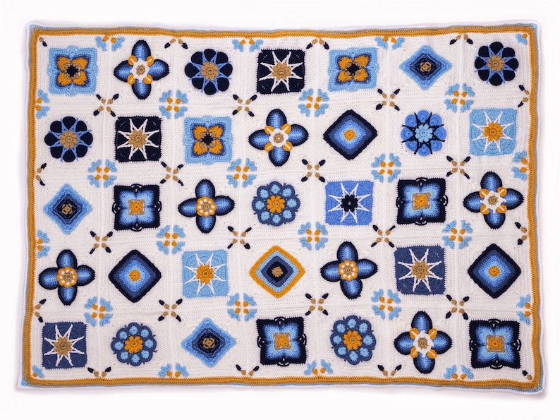 May include: A crocheted blanket with a white background and a pattern of blue and yellow squares. The squares are arranged in a grid pattern and each square has a different design.
