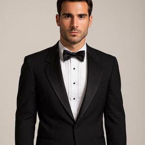 May include: A formal black tuxedo with a satin lapel, a white dress shirt, and a black bow tie. The suit has a single-button closure and is worn with black dress pants. The shirt has pleats down the front.