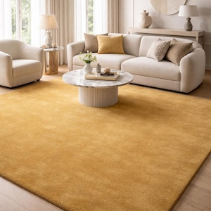 Puede incluir: Una alfombra rectangular grande de color amarillo mostaza sólido y vibrante. La alfombra presenta una textura densa de pelo corto que cubre el espacio del suelo, proporcionando una apariencia uniforme y suave en toda su superficie.