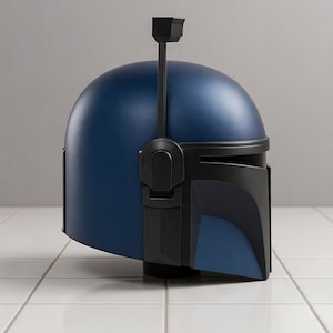 May include: A blue and black helmet with a matte finish. The helmet has a rounded top with a vertical antenna and a visor. The helmet is likely a costume piece or collectible.