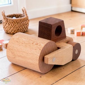May include: A wooden toy road roller with a large cylindrical roller and a dark brown cabin. The toy is made of light-colored wood and has a simple, classic design. The toy is designed for children.