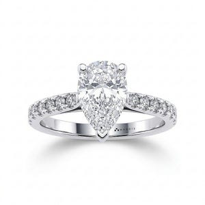 May include: A silver-toned ring featuring a large pear-cut center stone held by prongs, with a band encrusted with smaller round-cut stones along the sides. The interior of the band is engraved with the brand name MAKDIS in black lettering.
