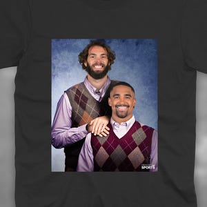 May include: A black t-shirt featuring a rectangular graphic print of two smiling individuals wearing light-coloured collared shirts under brown and maroon argyle sweater vests. The text "HIGHLIGHT SPORTS" is printed in the bottom right corner.