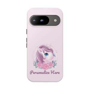May include: A light pink phone case featuring a unicorn design with a purple mane, blue eyes, and a butterfly. The unicorn is surrounded by pink roses and green leaves. The text "Personalize Here" is below the design.