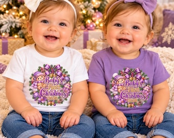 Può includere: Due neonati con jeans blu e magliette con il disegno di un orsetto in una ghirlanda e la scritta Baby's First Christmas 2026. Uno indossa una maglietta bianca e una fascia bianca, l'altro una maglietta viola e una fascia viola.