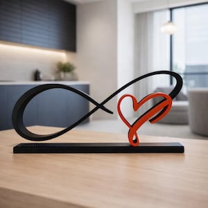 May include: A black metal sculpture featuring an infinity symbol intertwined with a red heart. The piece is mounted on a black base. It is displayed on a light wood table in a modern living room setting.