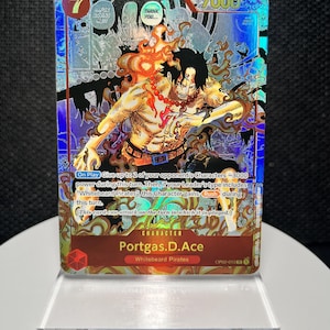 May include: A holographic One Piece trading card featuring Portgas D. Ace with a cost of 7 and 7000 power. The card displays a dynamic illustration of the character surrounded by flames, with text detailing game mechanics and the Whitebeard Pirates affiliation.
