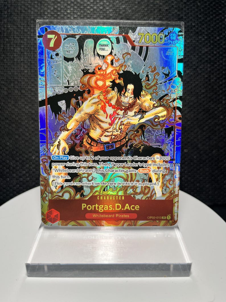 May include: A holographic One Piece trading card featuring Portgas D. Ace with a cost of 7 and 7000 power. The card displays a dynamic illustration of the character surrounded by flames, with text detailing game mechanics and the Whitebeard Pirates affiliation.