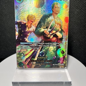 以下が含まれることがあります： ロロノア・ゾロとサンジが描かれたホログラフィック仕様のワンピーストレーディングカード。カードには「Roronoa Zoro」、「Supernovas/Straw Hat Crew」、および「Blocker」能力の説明が記載されています。コストは4、パワーは4000で、斬属性アイコンが表示されています。