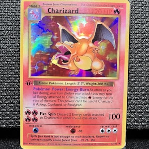 May include: A Charizard Pokémon card, Stage 2, with a holographic background. The card features an orange dragon with black wings, and the text "Charizard" and "120 HP". The card is 5' 7" long and weighs 200 lbs.