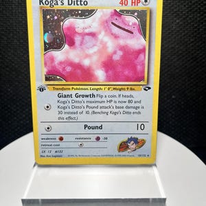 May include: A Koga's Ditto trading card featuring a pink, amorphous creature illustration. The card displays 40 HP, the Giant Growth and Pound attacks, and includes text detailing the Pokémon's stats, abilities, and the 1st Edition symbol.