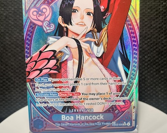 May include: A holographic One Piece trading card featuring the character Boa Hancock with long black hair, wearing a red and white outfit. The card displays game text, a power level of 8000, and pink heart icons against a blue and purple background.