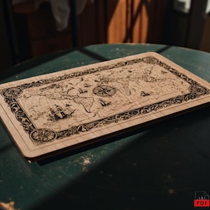 Könnte beinhalten: Eine rechteckige Weltkarte aus Holz mit aufwendigen Laserschnittdetails. Die Karte zeigt eine Windrose, Schiffe und dekorative Bordüren. Das helle Holz kontrastiert mit den dunklen geätzten Linien und erzeugt ein detailliertes Kunstwerk.