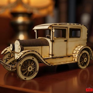 May include: A wooden model of a vintage car, with a light brown body and dark brown hood. The car has detailed wheels and a classic design. The model is set on a dark brown surface, ideal for display. The car is made of wood.