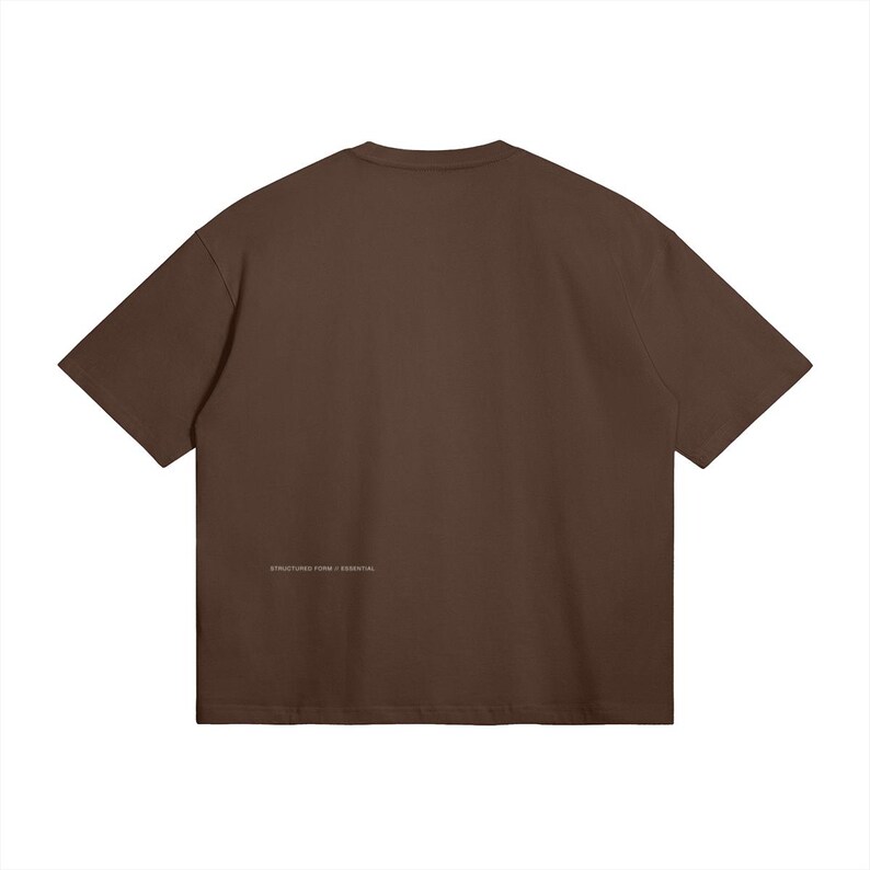 May include: A solid brown t-shirt with short sleeves. The back of the shirt features the text "STRUCTURE FORM / ESSENTIAL" in small, light-colored lettering near the bottom hem. The shirt is made of a soft, opaque material.