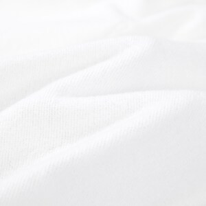K&ouml;nnte beinhalten: Eine Nahaufnahme von wei&szlig;em Stoff mit einer sichtbaren Webstruktur. Das Material ist gefaltet und erzeugt weiche, abgerundete Kanten und tiefe Schatten, die das Oberfl&auml;chenmuster des Textils und die helle, reine wei&szlig;e Farbe des Stoffes betonen.