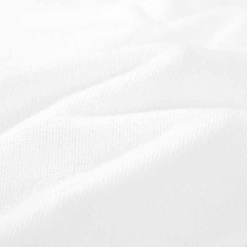 K&ouml;nnte beinhalten: Eine Nahaufnahme von wei&szlig;em Stoff mit einer sichtbaren Webstruktur. Das Material ist gefaltet und erzeugt weiche, abgerundete Kanten und tiefe Schatten, die das Oberfl&auml;chenmuster des Textils und die helle, reine wei&szlig;e Farbe des Stoffes betonen.