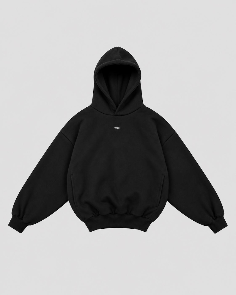 K&ouml;nnte beinhalten: Ein einfarbiger schwarzer Kapuzenpullover mit langen &Auml;rmeln, gerippten B&uuml;ndchen, einem gerippten Saum und einer ger&auml;umigen Kapuze. In der Mitte der Brust befindet sich der kleine wei&szlig;e Schriftzug WRN. Das Kleidungsst&uuml;ck besteht aus dickem Stoff.