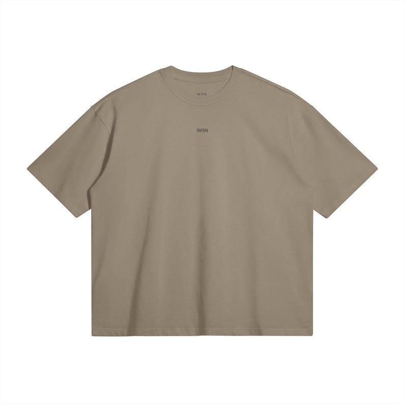 May include: A short-sleeved, taupe-colored t-shirt with a crew neck. The word "WRN" is printed in small, dark letters centered on the chest. The shirt has a relaxed fit and a minimalist design.