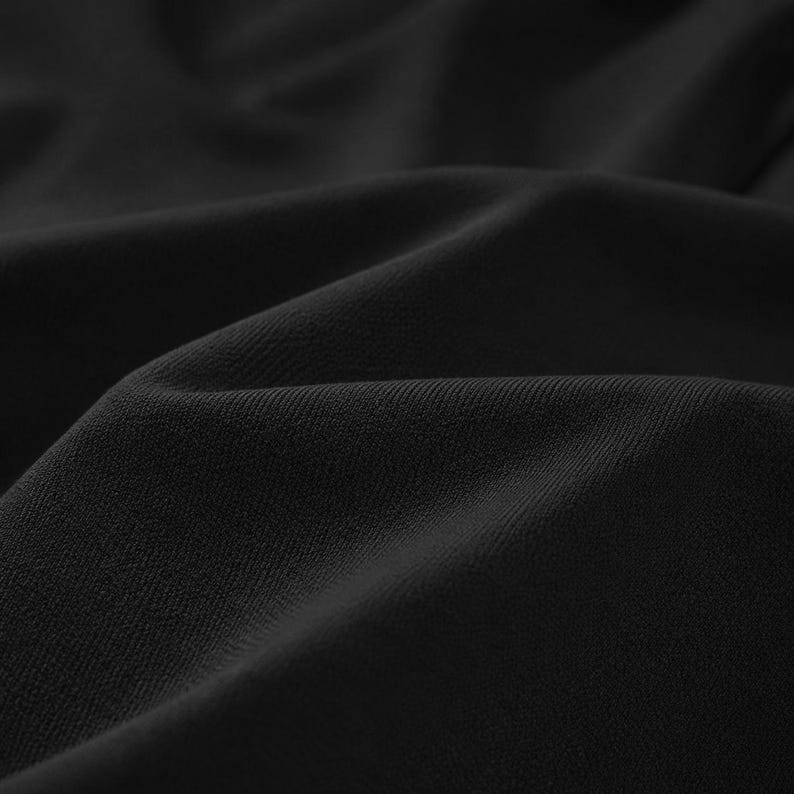 May include: Close-up of black fabric with a textured surface. The fabric is draped, creating soft folds and shadows. The material appears to be a medium-weight textile, suitable for clothing or home decor.