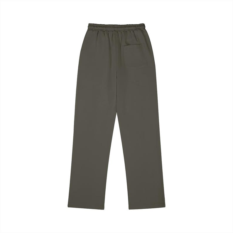 Puede incluir: Pantalones de ch&aacute;ndal de color verde oliva oscuro s&oacute;lido con cintura el&aacute;stica sin cord&oacute;n y un bolsillo de parche &uacute;nico situado en la parte superior derecha de la parte trasera. Los pantalones tienen un corte recto y un acabado liso sin estampados.