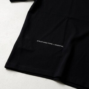 May include: A black t-shirt with the text "STRUCTURED FORM // ESSENTIAL" printed in white near the bottom. The shirt is made of a soft material and has a simple, minimalist design.