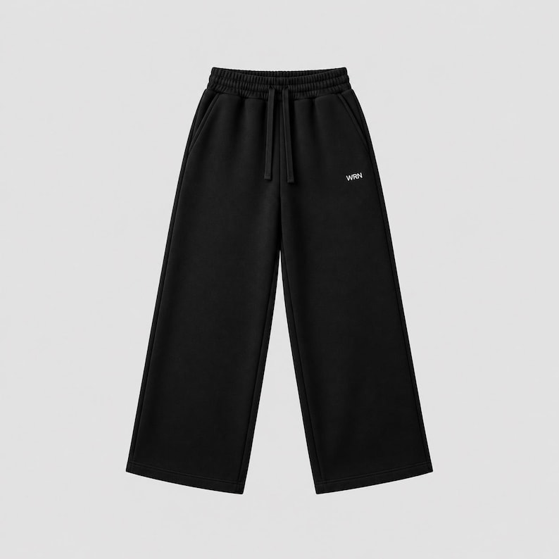 Puede incluir: Pantalones de ch&aacute;ndal negros con silueta de pierna ancha, cintura el&aacute;stica con cord&oacute;n a juego y dos bolsillos laterales. El texto WRN est&aacute; impreso en letras blancas peque&ntilde;as en la parte superior del muslo izquierdo de la prenda.