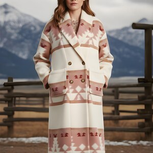 May include: A long, double-breasted coat in cream with a geometric pattern in shades of pink and brown. The coat features large pockets and a notched lapel. The background shows a mountain range and a wooden fence.