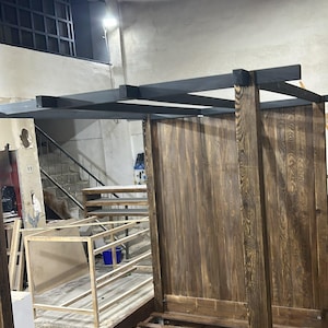 Close-up of wooden canopy bed post and handcrafted joinery showing the substantial solid wood construction