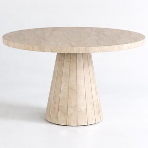 Round pedestal dining table in warm neutral interior with decorative vase and elegant table setting
