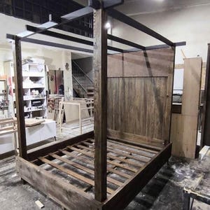Front view of a rustic canopy bed handcrafted from solid wood with tall four poster frame and natural wood grain
