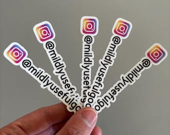 Op de afbeelding: Vier rechthoekige witte stickers in een waaiervorm. Elke sticker heeft bovenaan het kleurrijke Instagram-camera-icoon en daaronder de zwarte tekst @mildlyusefulgo verticaal gedrukt op een witte achtergrond.