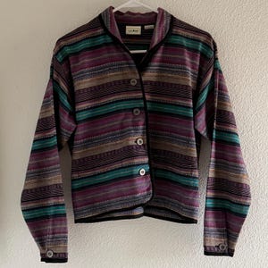 Può includere: Giacca abbottonata a righe nei toni del viola, verde acqua, marrone e beige. La giacca ha finiture e bottoni neri. L'etichetta recita "L.L.Bean".