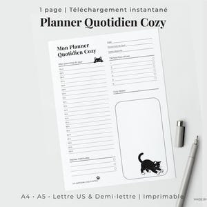 May include: A white daily planner sheet with the text "Planner Quotidien Cozy" and a black cat illustration. Includes sections for daily scheduling, notes, and habits. A pen and a small cylindrical object are next to the planner.