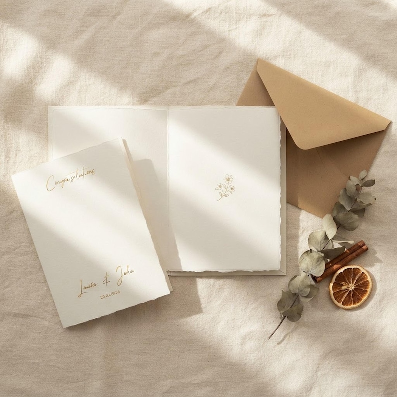 Flat lay showing the open card interior with the coordinating brown envelope and botanical accents.