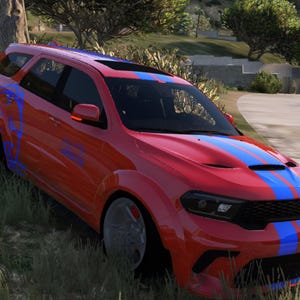 Puede incluir: Un SUV rojo con rayas azules en el capó y el techo. El vehículo tiene gráficos azules en el lateral y está estacionado en una zona de césped junto a una carretera. El coche tiene llantas negras.