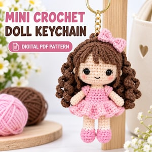 Puede incluir: Un llavero de muñeca de ganchillo con cabello castaño rizado, un vestido rosa y un lazo rosa a juego. La muñeca tiene ojos negros y mejillas sonrosadas. El texto en la imagen dice: MINI CROCHET DOLL KEYCHAIN y DIGITAL PDF PATTERN.