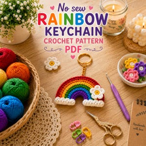 May include: A crocheted rainbow keychain with a white flower accent, gold-colored hardware, and a variety of colorful yarn balls in a basket. The image also includes a crochet hook, scissors, and the text "No sew RAINBOW KEYCHAIN CROCHET PATTERN PDF."