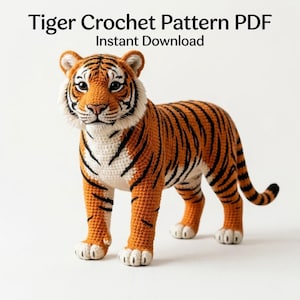 May include: A crocheted tiger in orange, black, and white, standing on a white surface. The tiger has black stripes and is made with a textured yarn. The text "Tiger Crochet Pattern PDF Instant Download" is at the top of the image.